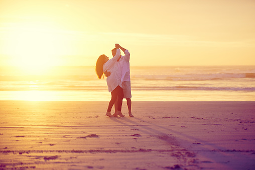 Full length shot of an affectionate mature couple dancing on the beach at sunset
