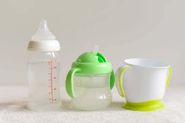 tre tipi di bottiglie e tazze con acqua per il bambino. - baby cup foto e immagini stock