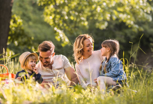 молодая счастливая семья наслаждается пикником в весенний день в лесу. - family with two children family park child стоковые фото и изображения