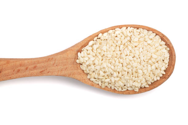 istock Sesame seeds in a wooden spoon isolated on white background top view 871103480