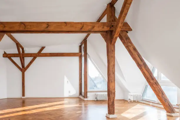 Photo of empty loft room with wooden framework and parquet floor