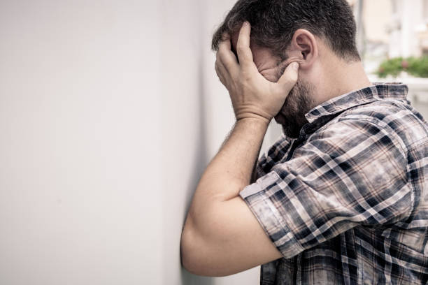 istock portrait one sad man standing near a wall and covers his face 871112970