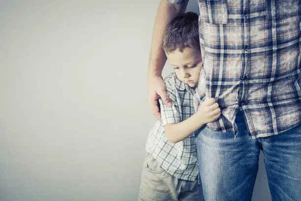 sad son hugging his dad near wall at the day timesad son hugging his dad near wall at the day time