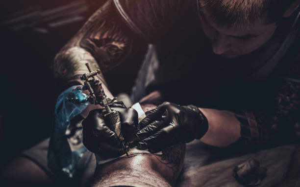 istock Tattoo master making tattoo on customer's leg 871115962