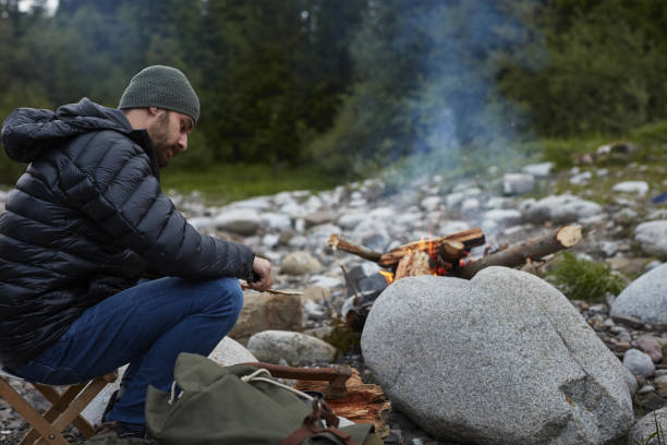 istock Young man relaxing by the fire. Mountainous landscape 871117332