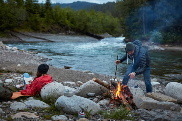 istock Young couple making a bonfire. Mountainous landscape 871117430