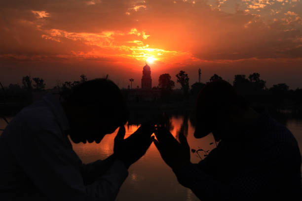 Two young worshipper doing meditation towards the temple during sunset time.