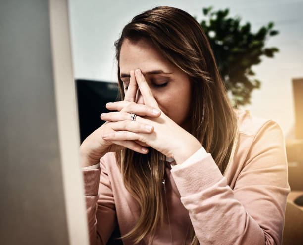 istock Blonde woman at computer clasps hands and closes eyes 871125584