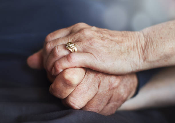 senior married couple's hands, tightly clasped together - wedding ring love engagement imagens e fotografias de stock