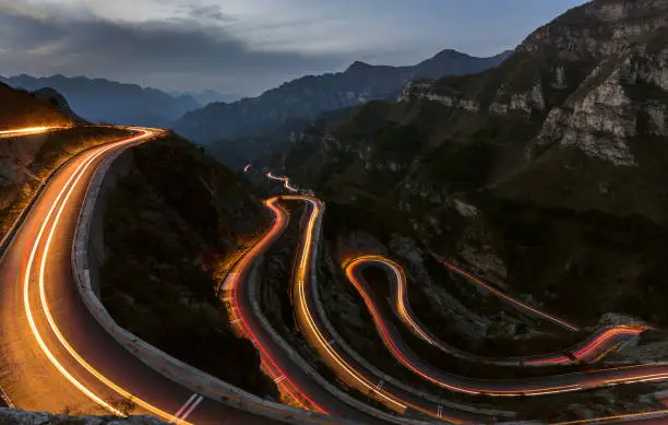 Winding road with hairpin bends up the at dusk with traffic lights.