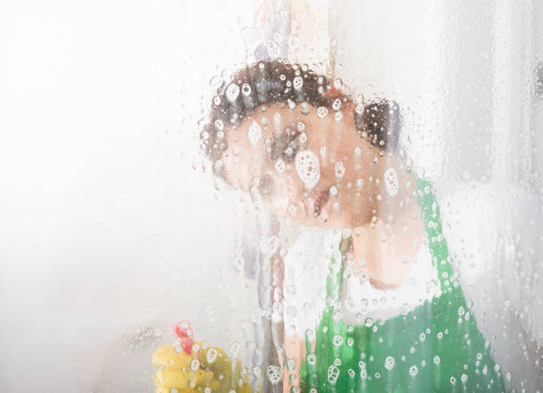 istock Housekeeping woman cleaning window with spray 871156526