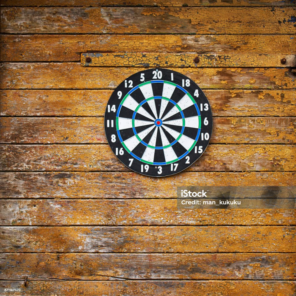 Dart board on a wooden grunge wall Dart board on a wooden grunge plank wall Accuracy Stock Photo