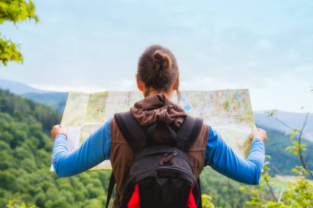 バックパックを持つ女性旅行者は荒野地域、実際のエクスプ ローラーに方向を検索するマップをチェックします。旅行の概念 - mountain footpath hiking backpacker ストックフォトと画像