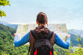 Woman traveler with backpack checks map to find directions in wilderness area, real explorer. Travel Concept
