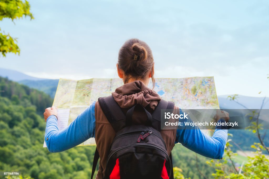 Woman traveler with backpack checks map to find directions in wilderness area, real explorer. Travel Concept Hiking woman traveler with backpack checks map to find directions in wilderness area, real explorer. Travel Concept Map Stock Photo