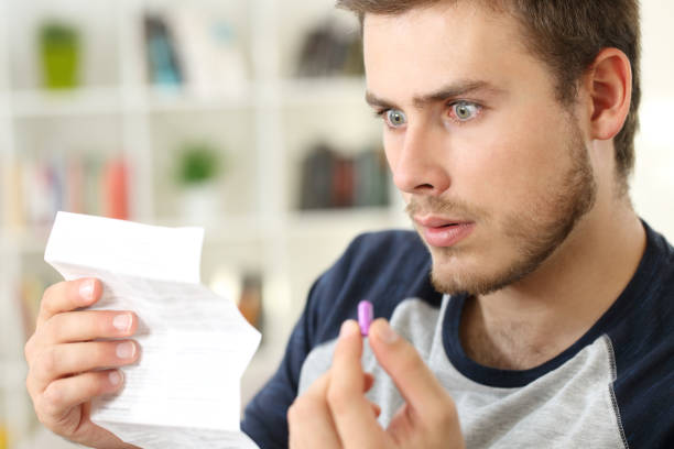 istock Shocked man reading a leaflet before to take a pill 871176618