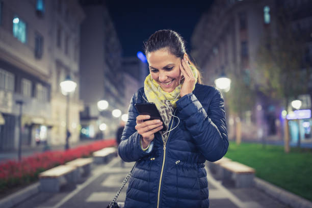 istock Single. Young woman with headphones using a phone while walking 871189264