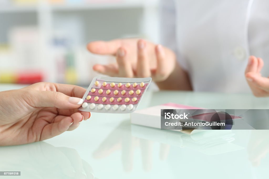 Girl buying contraceptive pills in a pharmacy Close up of a girl hands buying contraceptive pills and pharmacist explaining in a pharmacy Contraceptive Stock Photo