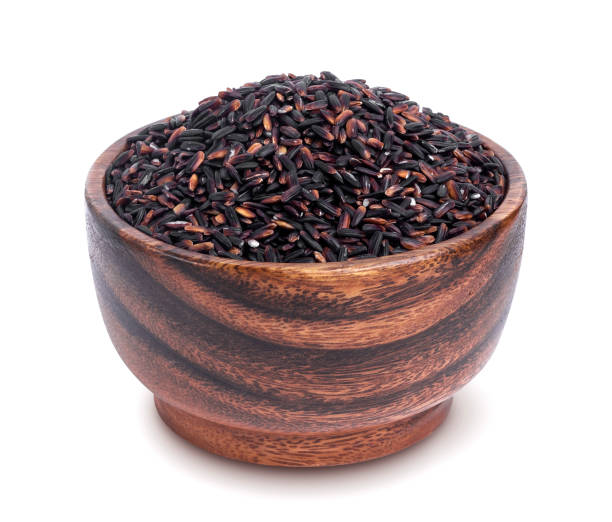 istock Black rice in wooden bowl isolated on white background 871195912