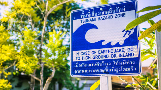 Tsunami Hazard Zone Earthquake Evacuation Warning Sign A Tsunami Hazard Zone warning sign near the waters edge in Koh Lanta, Thailand.  The instruction being in case of Tsunami or Earthquake, go to high ground or inland.  These advisory evacuation signs were erected following the Indian Ocean Tsunami on 26 December 2004, where 230,000 people were killed in 14 countries.  They are written in Thai and English and are common place throughout coastal areas. 2004 indian ocean earthquake and tsunami stock pictures, royalty-free photos & images