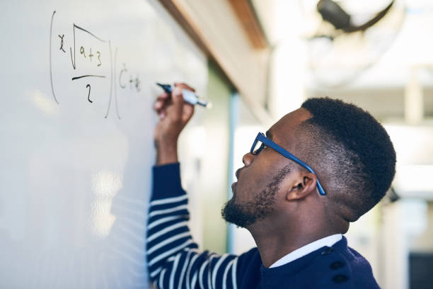 Just try until you get it right Cropped shot of a young man writing on a whiteboard in a classroom mathematics photos stock pictures, royalty-free photos & images