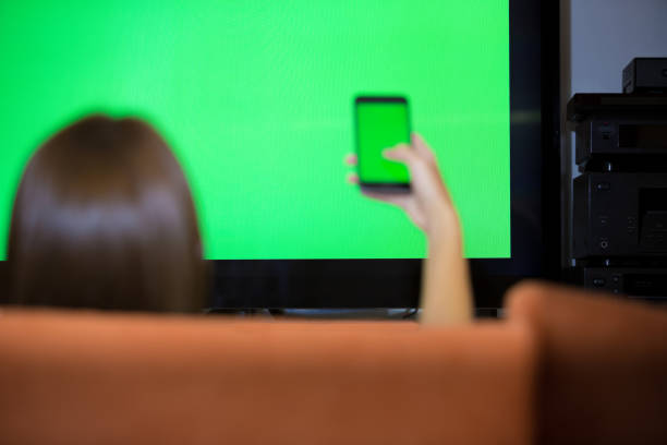 istock Lady Interacts Smart Phone and TV Green Screen 871204950