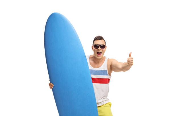 istock Joyful surfer with a surfboard making a thumb up sign 871208740