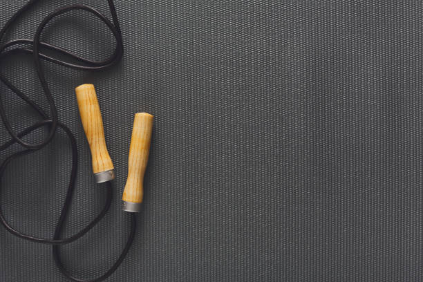Top view of jump rope on black background. Skipping rope, fitness supply, weightloss, slimming concept