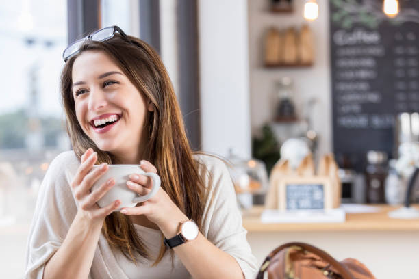 istock A young woman laughs during coffee break at coffee shop 871230968