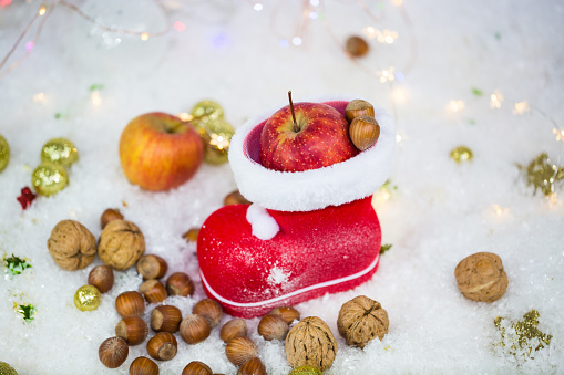 Santa Claus boots with nuts, tangerines, apples, in the snow