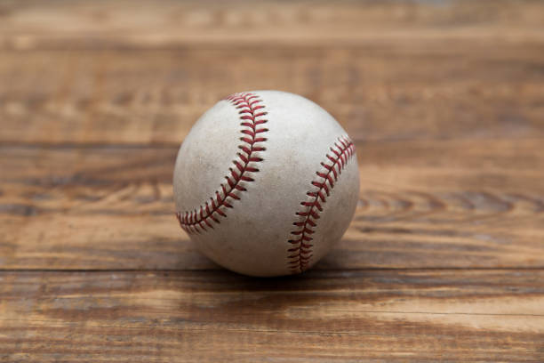 istock Baseball on a old rustic wooden desk with partial blur background 871239770