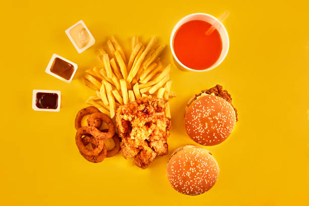 istock Fast food concept with greasy fried restaurant take out as onion rings, burger, fried chicken and french fries as a symbol of diet temptation resulting in unhealthy nutrition 871250946