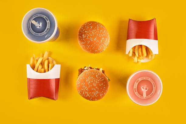 Fast food and unhealthy eating concept - close up of fast food snacks and cold drink on yellow background Fast food and unhealthy eating concept - close up of fast food snacks and cold drink on yellow background. Top view. Copy space. Still life. Flat lay. soda photos stock pictures, royalty-free photos & images