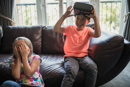 On the settee with one kid wearing virtual reality headsets.