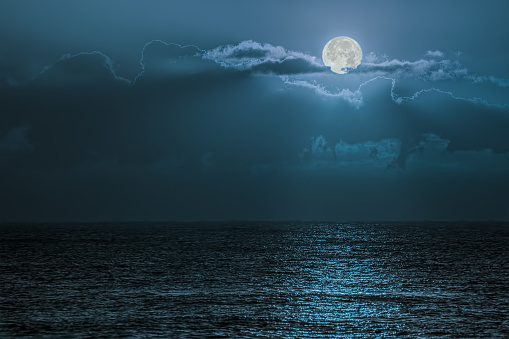 Blue moon light reflecting off ocean. Romantic twilight moonlight glistening off the surface of sea water. Lunar influence.