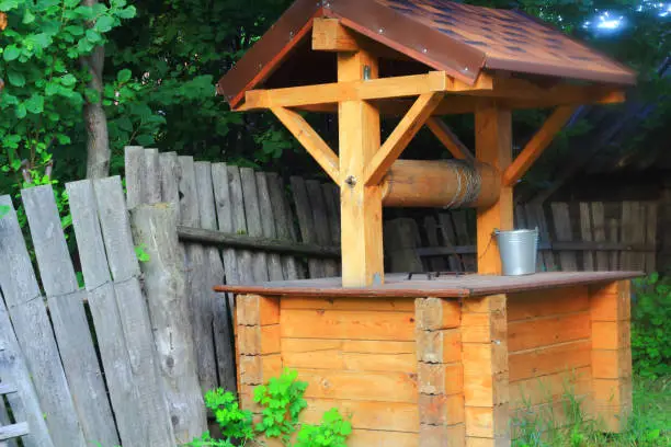 A village well made of wood with a galvanized bucket on a chain