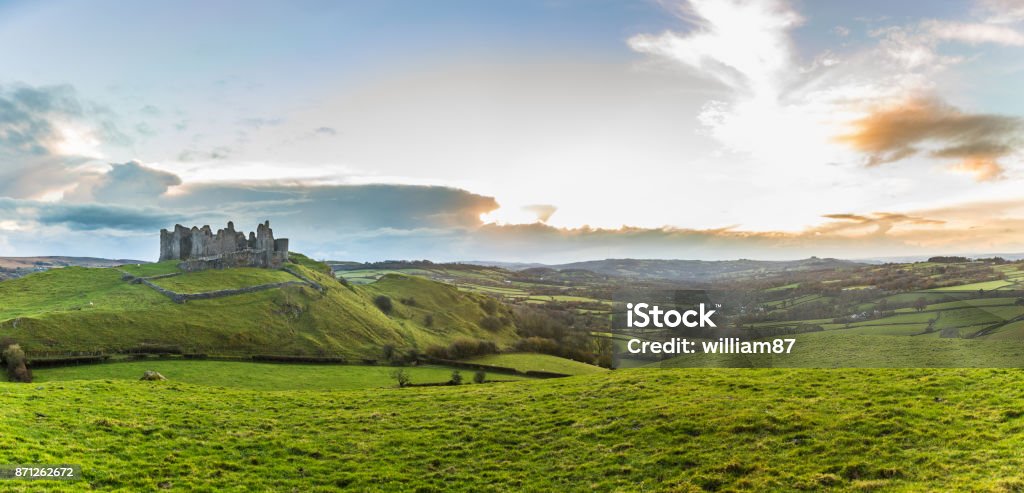 Countryside panorama with ruined castle on a hill at sunset Countryside panorama with ruined castle on a hill. Welsh scenery at sunset, panoramic photo, with green meadows on foreground. Nature and travel concepts Wales Stock Photo