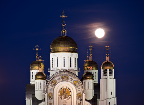 Orthodox cathedral in Magnitogorsk with golden domes and full moon behind