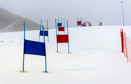 Children skiing slalom racing track with blue and red gates. Small ski race gates on a pole with children skiing in the background.