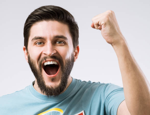 Bearded man facial emotions series Portrait of cheerful enthusiastic bearded man with fist up as sign success godspeed stock pictures, royalty-free photos & images