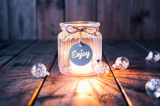 Cute christmas decoration with a light in a jar and some christmas ornaments. Jar is decorated with a bow and a label with the word Enjoy.