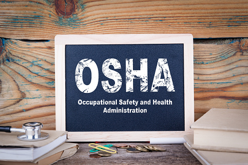 la OSHA administración de salud y seguridad ocupacional. Pizarra sobre un fondo de madera photo