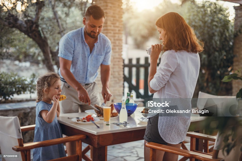 Father and dauther having mediterranean dinner on a terrace Father and dauther having mediterranean dinner on a terrace in a olive garden during summer vacation Summer Stock Photo