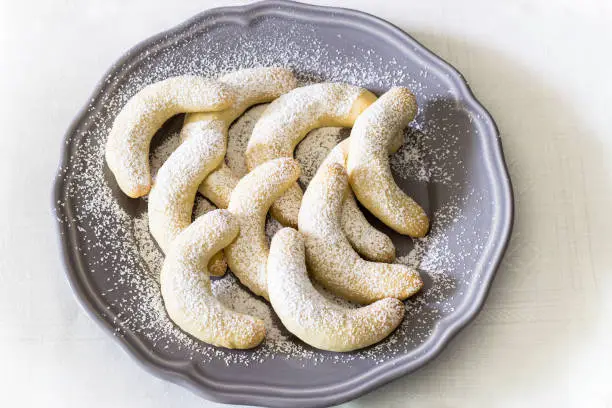 German Christmas pastries: vanilla crescent vanillekipferl on grey plate. White towel background. Top view. Christmas concept.