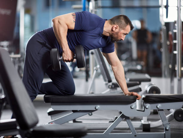 istock Fitness trainer with dumbbell row 871308952