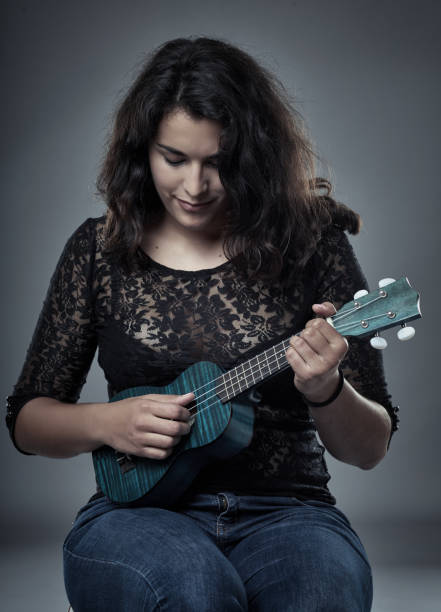 istock Young latino woman playing ukulele 871308986
