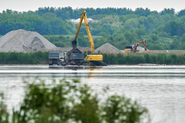 istock Excavator loading a truck on a lake 871316718