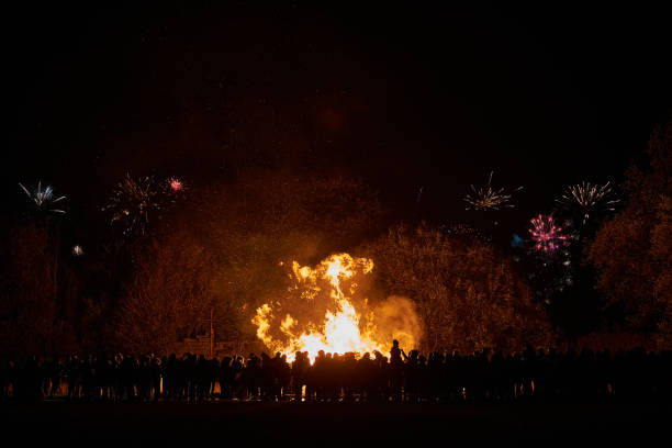 Bonfire and Fireworks A crowd watches a blazing with fireworks in the sky. firework display pyrotechnics celebration excitement stock pictures, royalty-free photos & images