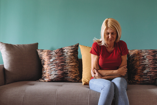 Mature or senior woman in her late 50s having pelvic pain while doing houseworks or during resting. Woman is going through the pain and suffer due to pelvic inflammatory disease.