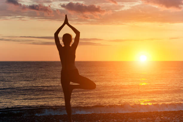 istock Girl at sunset practicing yoga at the seashore, silhouette 871319426